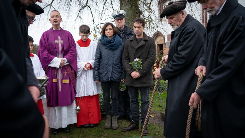 Eine Kollege von Ina Behrendsen (Julia Brendler) und Hinnerk Feldmann (Oliver Wnuk, dritter von rechts) wird zu Grabde getragen. Pfarrer Tillich (Peter Jordan) hält die Ansprache. "Polizeichef" Sievers hat Probleme mit seinem Fahrrad - und kommt zu spät.