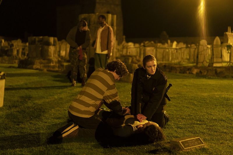 In den Morgenstunden des 26. Juni 1996 findet PC Janice Hogg (Gemma McElhinney, rechts) die Leiche der jungen Rosie (Anna Russell-Martin) auf dem Friedhof von St. Andrews. Die Studenten Ziggy (Jhon Lumsden, vorne), Weird (Jack Hesketh, links hinten) und Alex (Buom Tihngang) machen nur wenige brauchbare Angaben.