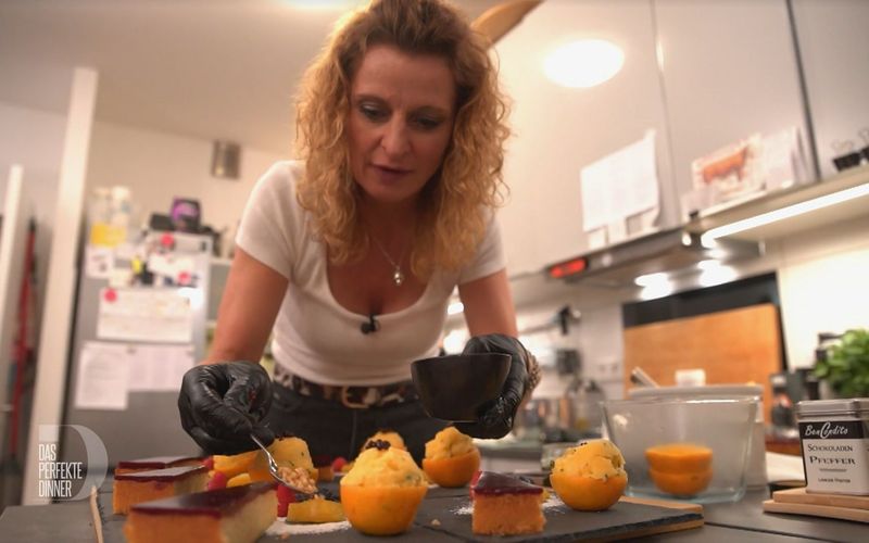 Jana dekoriert liebevoll Mandelkuchen und Orangen-Sorbet auf die Teller.
