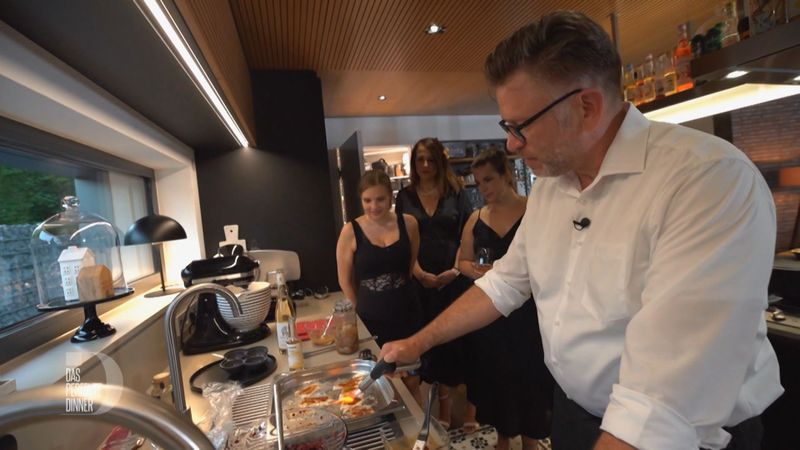 Show-Cooking zum Finale: Chris flämmt seine Forelle mit dem Bunsenbrenner. Tabea, Magda und Carmen schauen gespannt zu.
