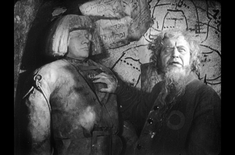 Rabbi Löw (Albert Steinrück, rechts) fabriziert in seinem Labor den Golem (Paul Wegener).
