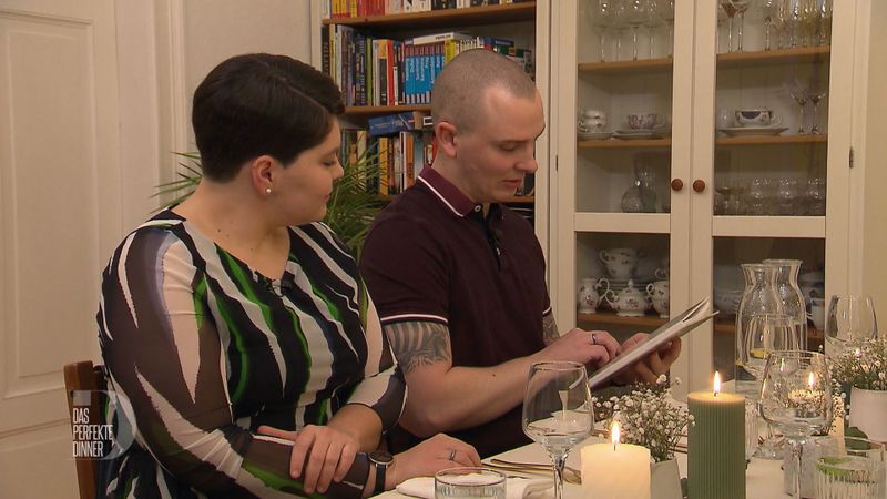 Beim Warten auf die Vorspeise entdecken Vicky und Paul Lisas Kochbuch im Bücherregal.
