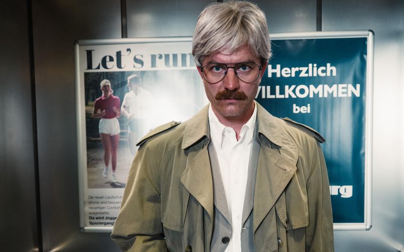 Arno Funke (Friedrich Mücke) besucht mal wieder im Cameo-Outfit eine Kaufhaus-Filiale - um einen kleinen Sprengsatz zu zünden. Damit will er in den 90-ern den Karstadt-Konzern, der in der Serie Harburg heißt, um hohe Summen erpressen.
