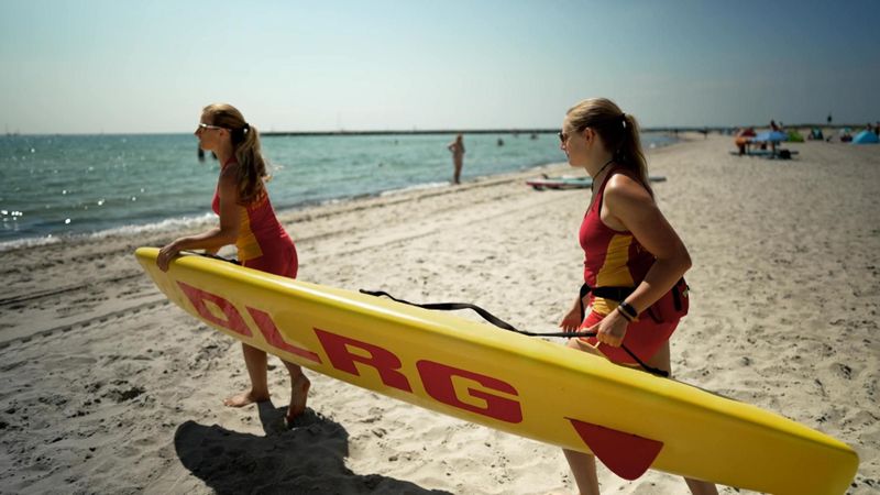 Am Strand von Scharbeutz an der Ostsee setzen sich die DLRG-Retterinnen in Bewegung, um einen Jungen aus den Fluten zu ziehen.