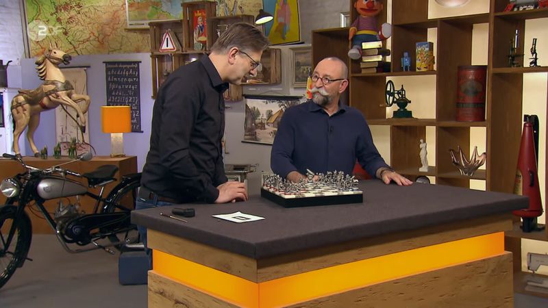 Ein Schachbrett sollte verkauft werden. Doch Horst Lichter (rechts) und Detlev Kümmel wollten erst mal damit spielen. Als der Moderator den Springer neu positionierte, krittelte Kümmel, es sei "völliger Quatsch, da hin zu springen". Ungläubig fragte er: "Was willst du da?"