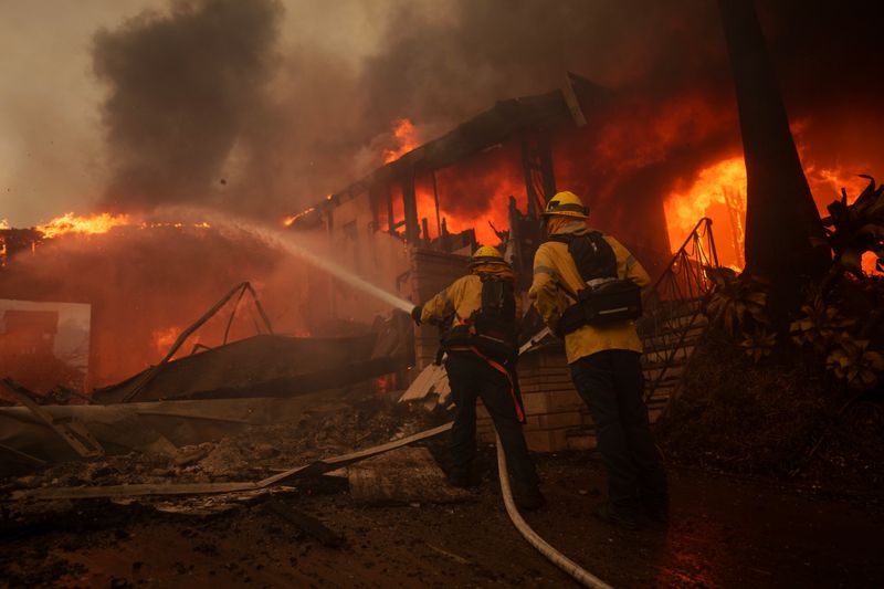 Feuerwehrleute bekämpfen die Flammen im Stadtteil Pacific Palisades von Los Angeles, Kalifornien. Das sich schnell ausbreitende Feuer bedroht die Häuser des Küstenviertels bei starkem Wind und trockenen Bedingungen.